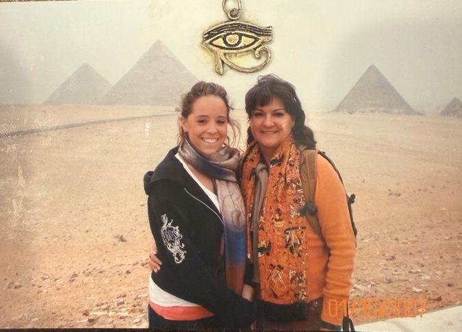 Two women standing together in front of the pyramids.